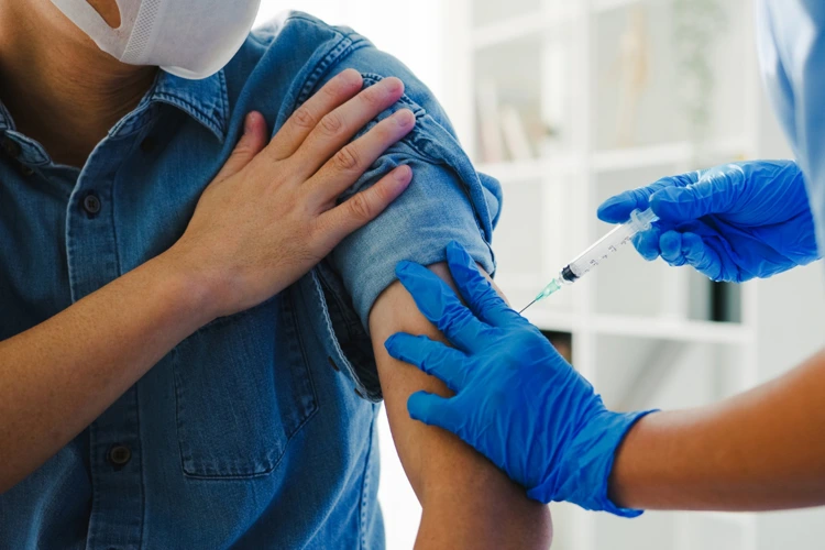 Nurse administering the influenza / flu vaccine jab to male patient.