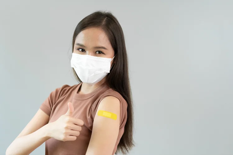 Woman with mask and bandage after JN.1 vaccination.