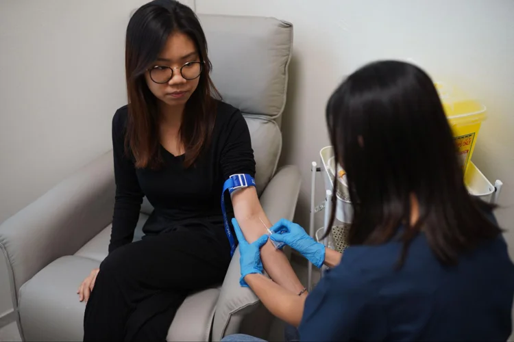 Nurse drawing blood from patient as part of health screening process.