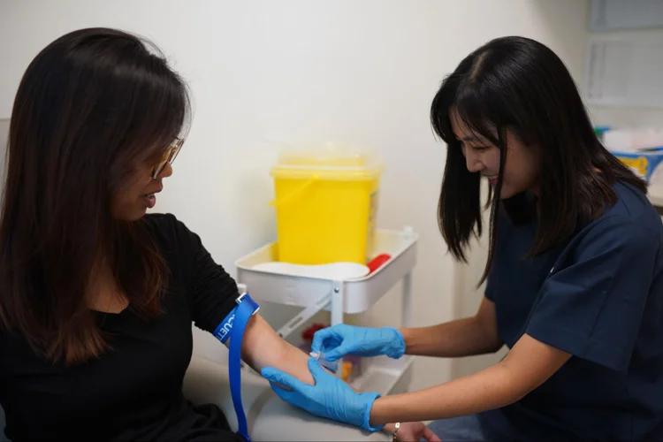 Nurse done with drawing blood process and applying pressure with cotton bud on patient's injected area.