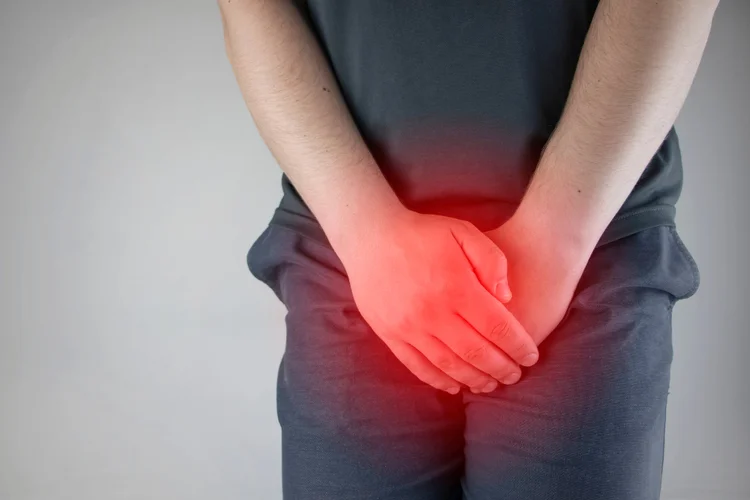 Man holding groin area in discomfort showing symptoms of Ureaplasma infection such as urinary pain.