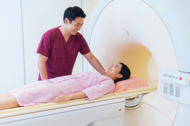 Patient lying on MRI scanner while staff assists during a full body MRI scan.