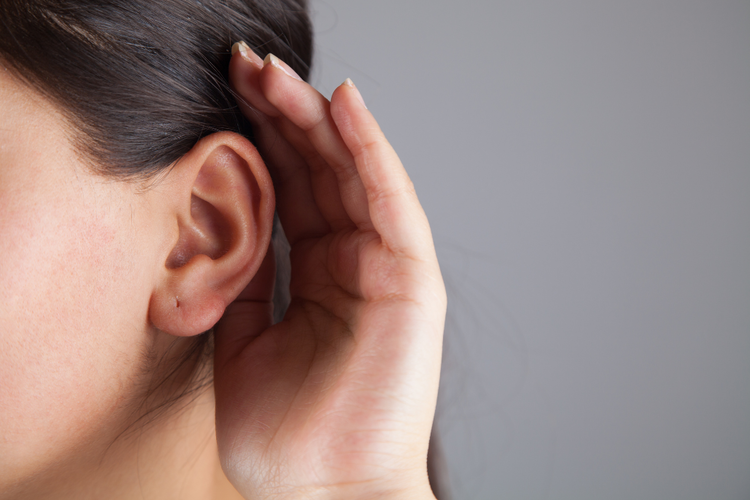 Person cupping ear to show difficulty hearing as symptom of conductive or sensorineural hearing loss.
