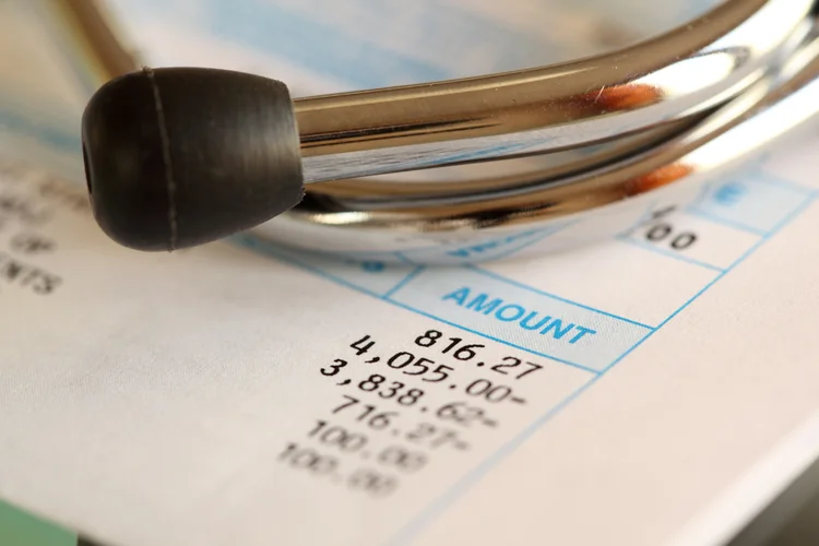 Stethoscope resting on invoice showing cost breakdown of private health screening packages.