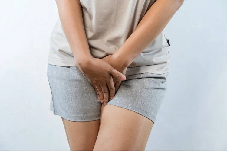 Woman holding pelvic area, showing discomfort from vaginal yeast infection symptoms.