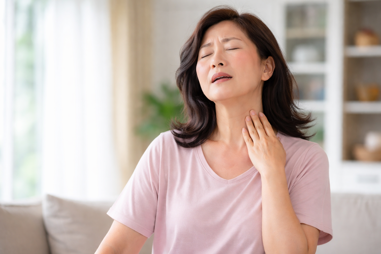 Woman experiencing hot flush, a common menopausal symptom tibolone can help manage.